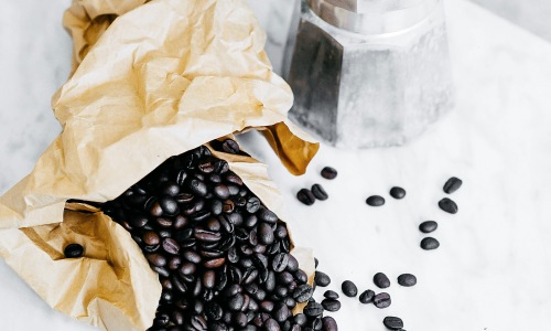 Coffee beans next to a percolator